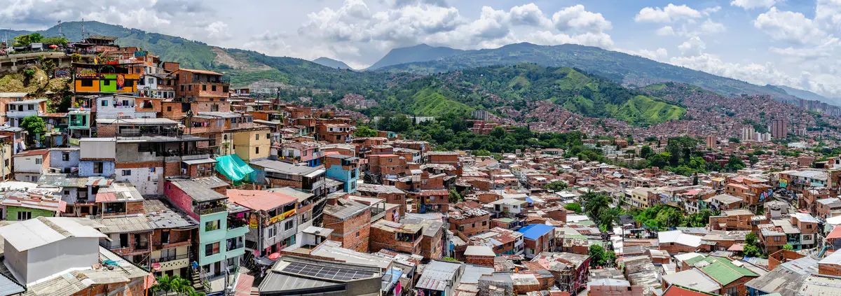 Casas de ladrillo y colores en la ladera de San Javier, la Comuna 13, con las montañas detrás.