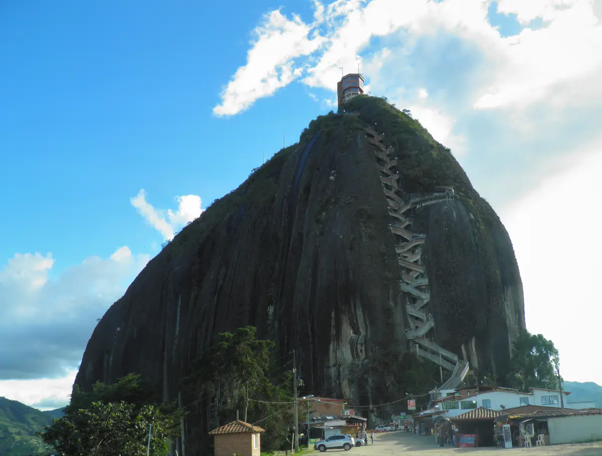 La Piedra del Peñol bajo un cielo azul, con su escalera en zigzag sobre la cara de la roca.