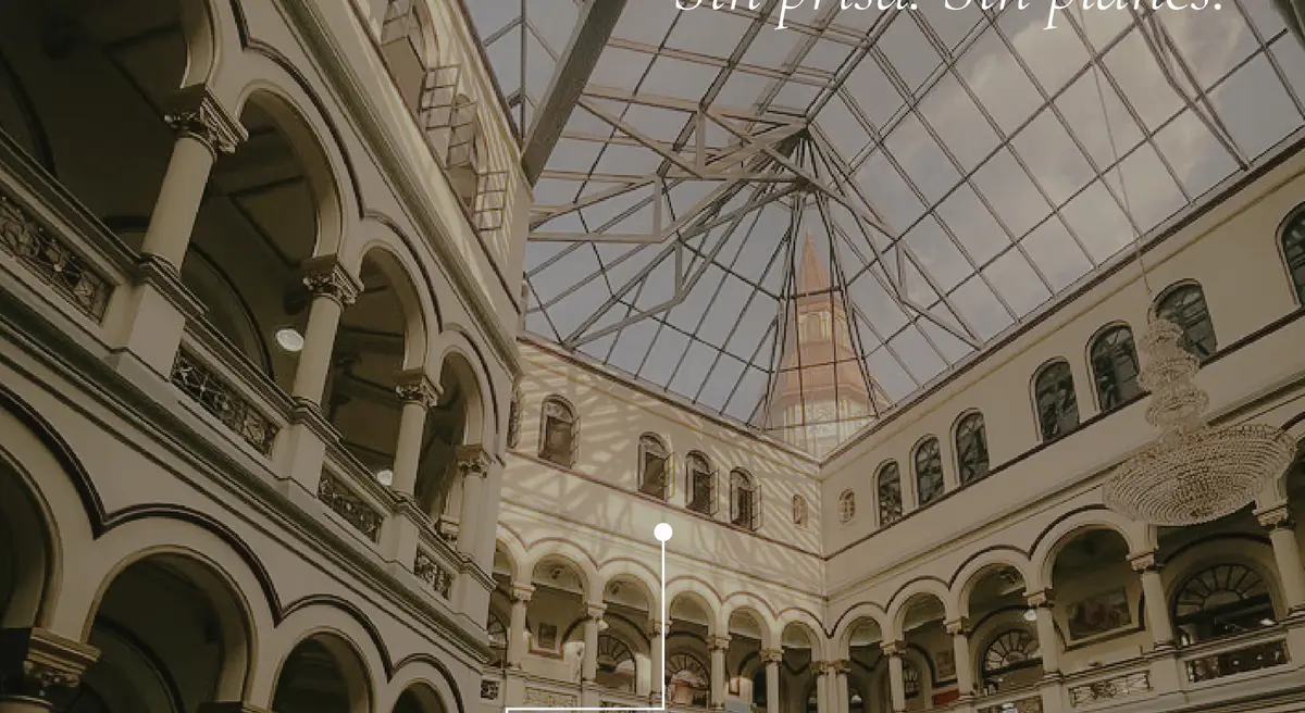 Patio interior con arcos superpuestos y techo de vidrio en un edificio histórico del centro de Medellín.
