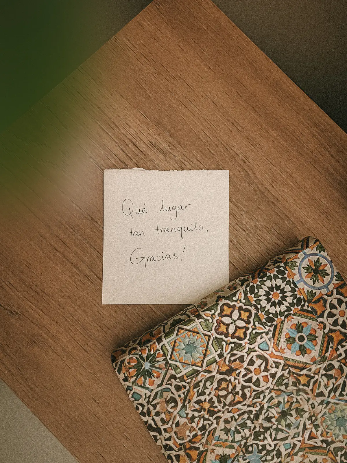 Nota escrita a mano sobre una mesa de madera: «Qué lugar tan tranquilo. Gracias!», junto a un estuche estampado.
